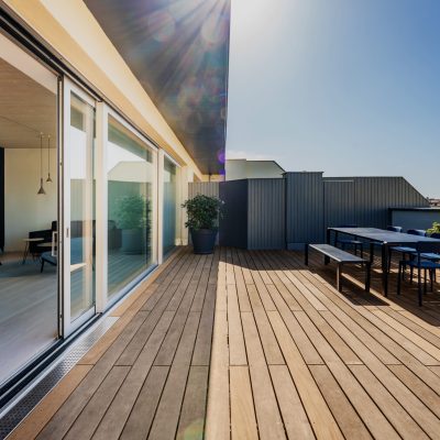 Hardwood rooftop patio deck with a picknick table and chairs. Floor to ceiling sliding doors open up to the loft apartment.